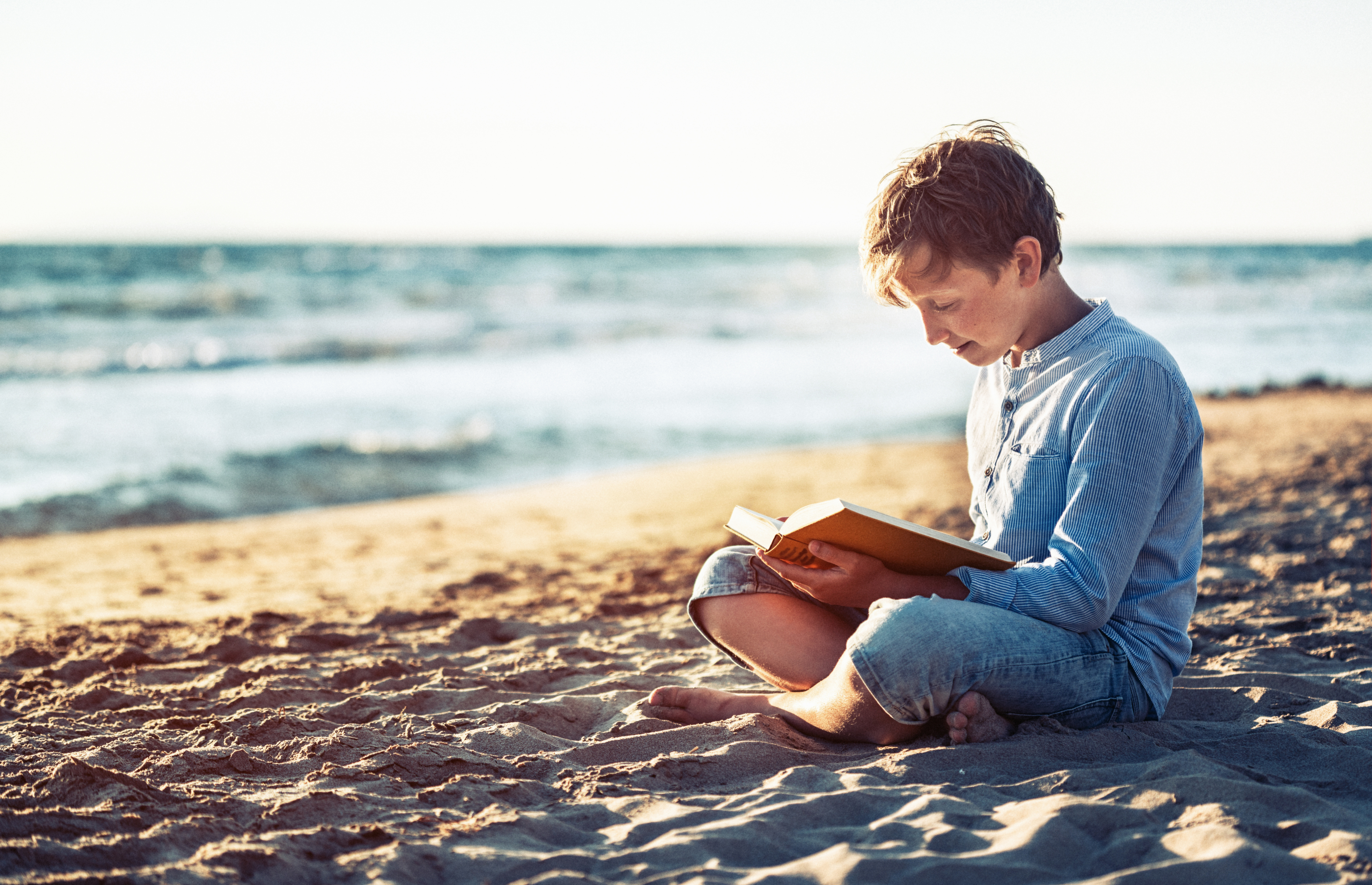 Книги молодому мужчине. Юноша читает книгу на пляжу. Чтение книги на море. Парень блондин читает. Книга лето Тоскливое.