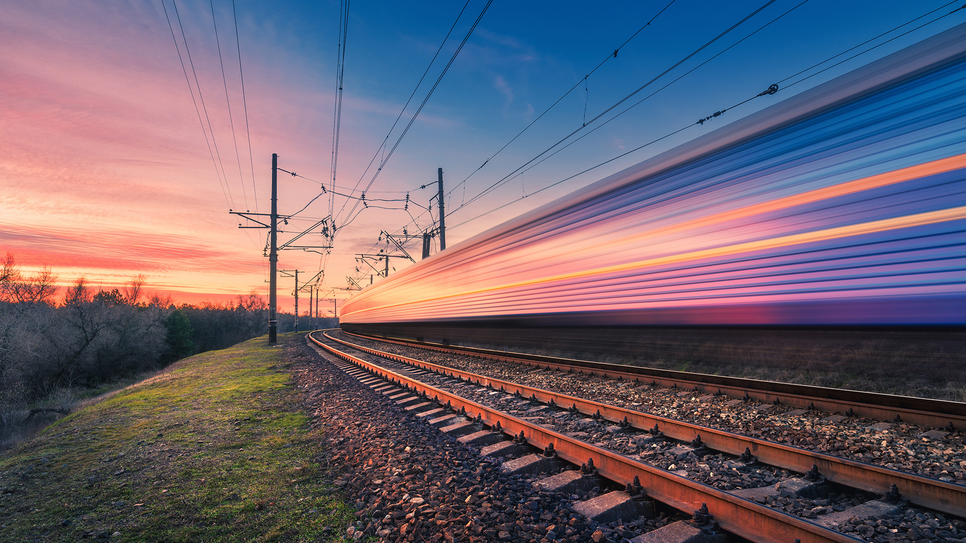 high-speed-passenger-train-in-motion-on-railroad-at-sunset-blurred