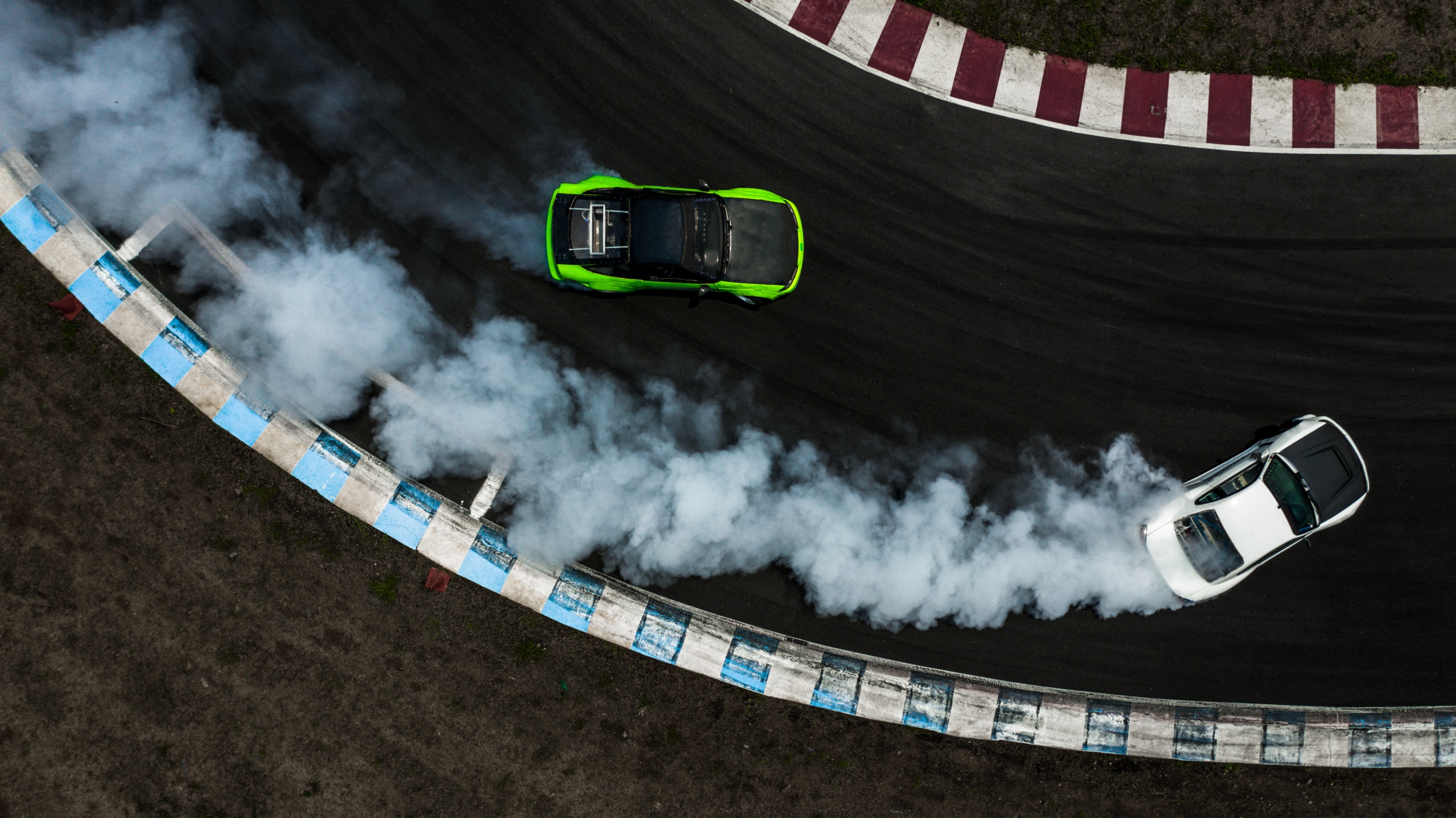 Two cars drifting battle on race track with smoke, Aerial view two